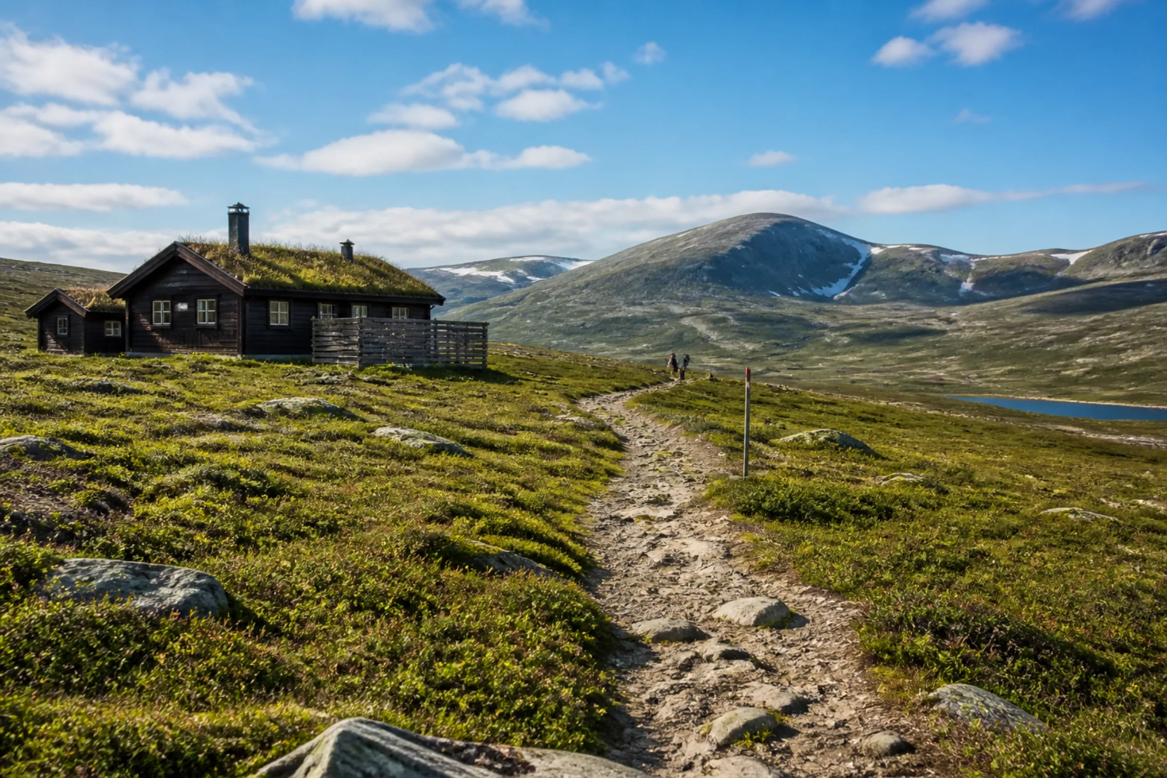 Fjällstuga sommartid med vandringsled och kalfjäll i bakgrunden
